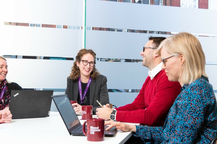 Blood Cancer UK staff members talking and smiling in the office.