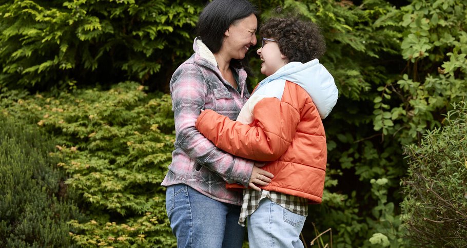 Alyssa and mum, Kiona, outside, facing each other and laughing as they embrace.