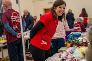 A woman wearing a Blood Cancer UK t-shirt at a fundraiser, smiling.