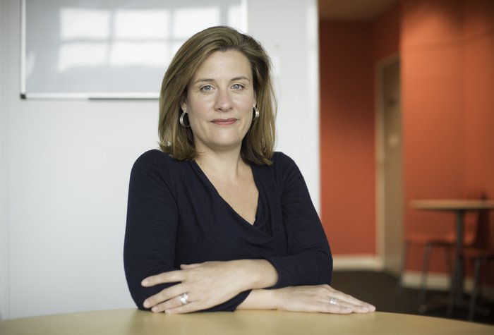 Gemma Peters, former CEO of Blood Cancer UK, sitting with her arms folded at a desk.