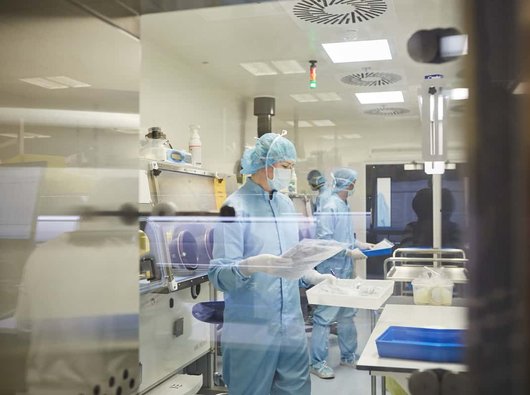 Three researches in full body personal protective equipment conducting tests in a research facility.