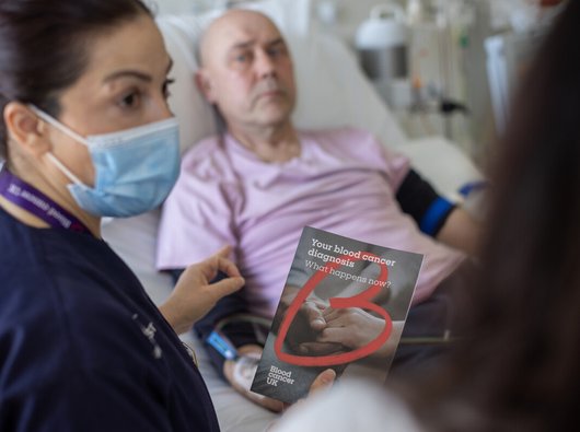 Nurse giving a patient a blood cancer uk flyer