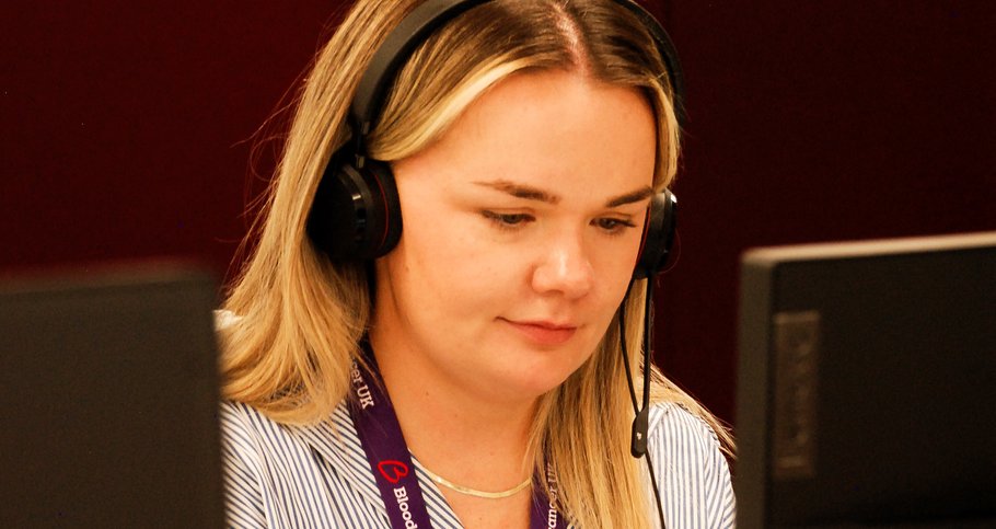 Rachel is sat looking at a laptop screen. She has a headset on and is speaking to someone on the phone.