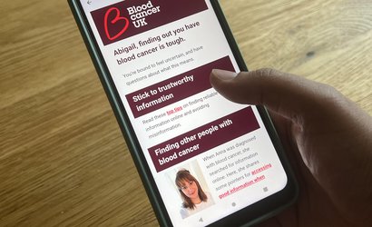 Photo of a hand holding a smart phone, looking at an email that talks about blood cancer information and support.