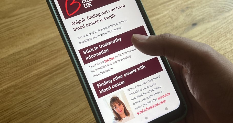 Photo of a hand holding a smart phone, looking at an email that talks about blood cancer information and support.