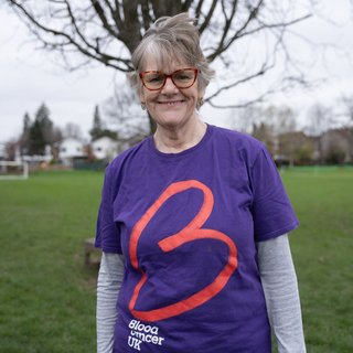 Female wearing purple Blood Cancer UK t shirt smiling to the camera