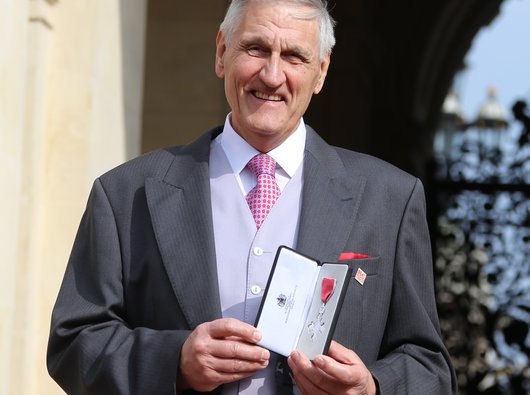 Richard Delderfield, a Blood Cancer UK Honorary President, in a three piece suit holding a medal.