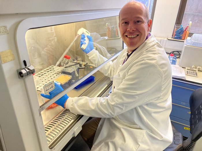Dr Robbert Hoogeboom smiling sat working in the lab.