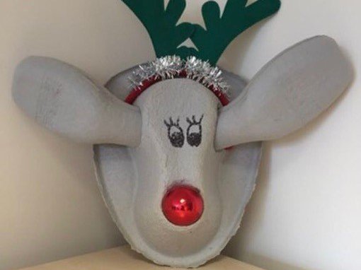 A bedpan that has been made into a Rudolph face using Christmas baubles and a reindeer headband.