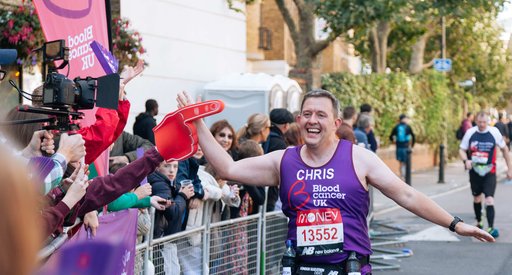 A runner high fives a supporter during a marathon. He wears a Blood Cancer UK vest.