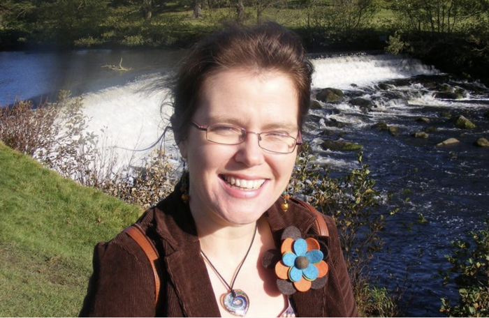 Joanna, who was diagnosed with chronic myeloid leukaemia (CML), standing beside a river smiling at the camera.