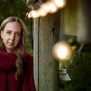 Molly outside in her winter jumper with Christmas lights around her.