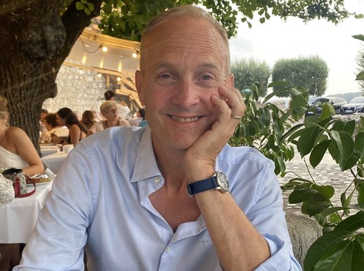 Stephen, smiling while sitting at an outdoor restaurant table
