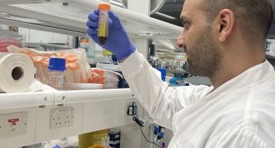 A man working in the lab holding a test tube, wearing a white lab coat.