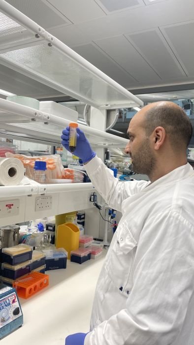 A man working in the lab holding a test tube, wearing a white lab coat.