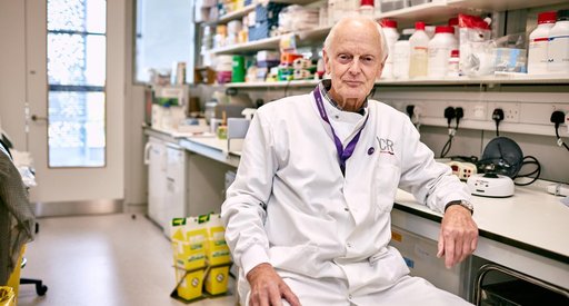 Professor Terry Rabbitts sitting in the lab wearing his lab coat