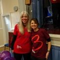 Laura and Victoria stand smiling at their stall at the Romsey Joint Charities Christmas Fayre, wearing Blood Cancer UK T-shirts.