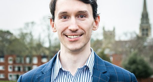 A man with dark hair wearing a blue suit smiling at the camera.