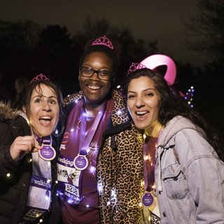 Three women stood together wearing tiaras and Walk of Light merchandise posing for the camera