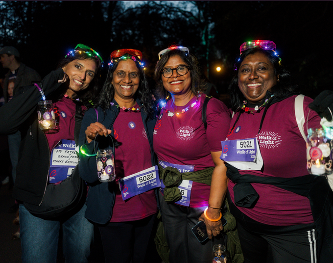 4 ladies stood next to each other in Walk of Light merchandise and lights on their heads