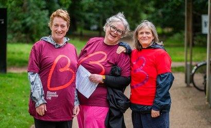 Three women wearing Blood Cancer UK t shirts smile at the camera.