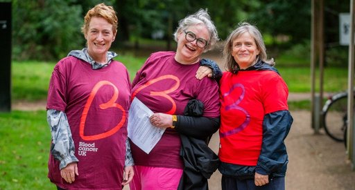 Three women wearing Blood Cancer UK t shirts smile at the camera.