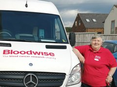 A Bloodwise van with its driver Chris posing alongside it.