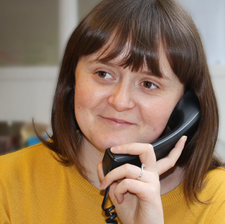 A stock close up image of a woman on the phone wearing a yellow top and looking away from the camera.