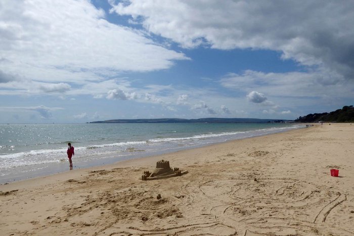 A beach scene with a sandcastle and the sea showing in the background.