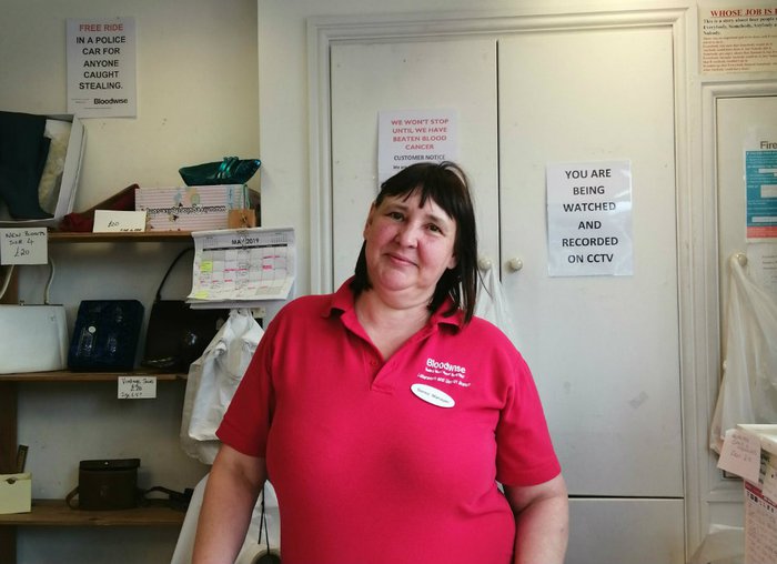 A woman behind the till at charity shop poses for a photograph.