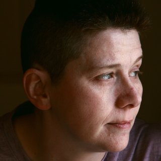 A person, alone, looking away with a thoughtful expression