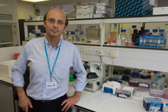 A male scientist - Professor Karadimitris - poses for a photograph in his lab