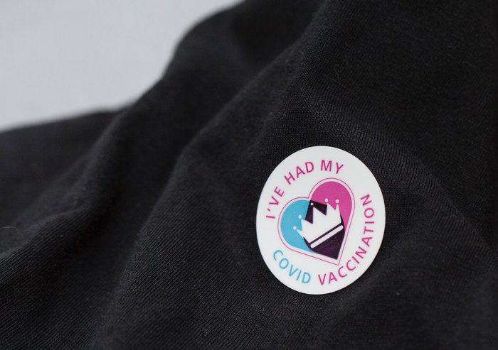 Close-up of a vaccination sticker showcasing that someone has had their Covid vaccine with a crown in the centre overlaying a heart.