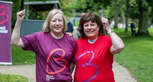 Two woman stand together smiling as they take on a walk of light charity step challenge.
