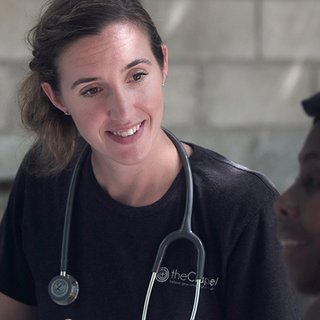 Doctor with stethoscope round neck talking to female patient about treatment.