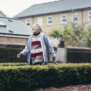 An older woman Eric strides happily down a suburban street on her way somewhere.