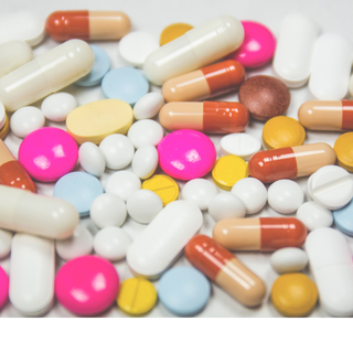 A selection of different white pills and colourful capsules close up.