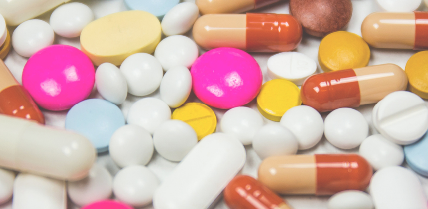 A selection of different white pills and colourful capsules close up.