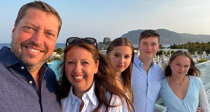 Matthew Wilson stands smiling with his family on a sunny evening in Summer.