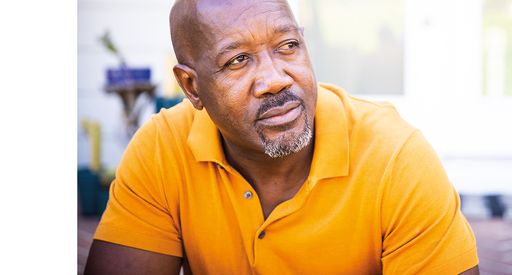 An older middle aged Black man in a yellow shirt.