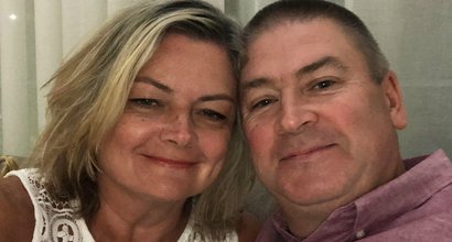 A middle aged couple pose for a photo together indoors