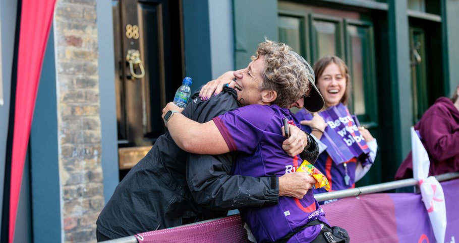 Two people embracing at a cheer point during a running event.