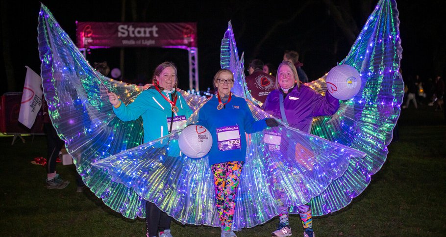 People standing in fairy-light costumes under the night sky at the Walk of Light.