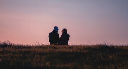 A couple out walking on a heath, seen from behind against the sky