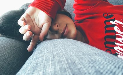 Woman lying on sofa looking tired.