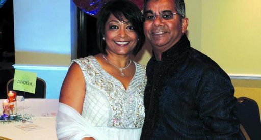 A middle aged couple pose for a photograph at a wedding.