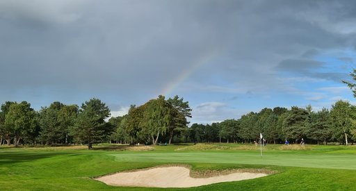 A rainbow shines over a beautiful green golf course